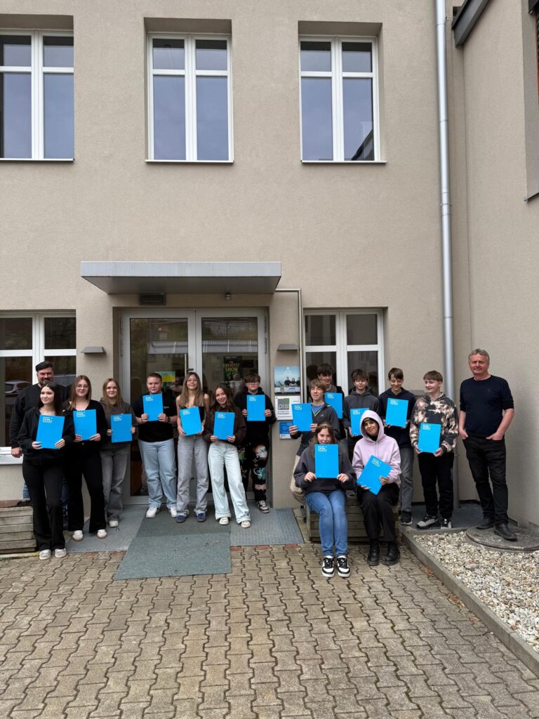 Schülerinnen und Schüler mit Urkunden vor Schulgebäude in Österreich